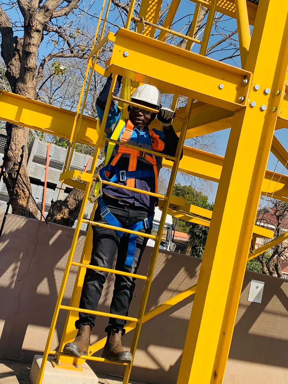 Makurung team member in full fall-protection harness ascending a training tower