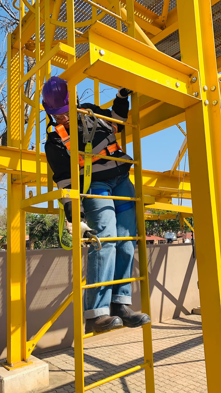 Team member climbing training tower with harness clipped in